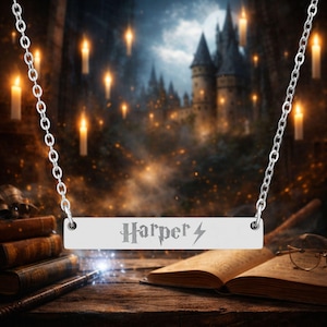 May include: Silver-toned necklace with a rectangular pendant engraved with the name "Harper" and a lightning bolt symbol. The necklace hangs against a backdrop of a castle, candles, and books, creating a magical theme.