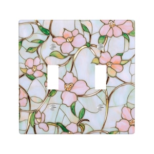 May include: A decorative light switch cover featuring a stained glass design. The cover has a square shape and is adorned with pink flowers, green leaves, and gold-colored stems against a pale blue background.