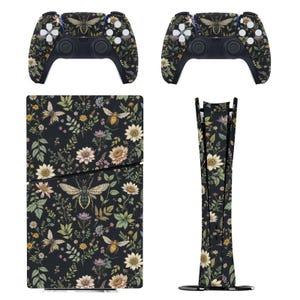 Könnte beinhalten: Ein Set von Gaming-Zubehör mit einem floralen und Insekten-Design. Das Set enthält zwei Controller, eine Konsolenhaut und eine vertikale Standfußhaut. Das Design zeigt Bienen, Blumen und Blätter auf schwarzem Hintergrund.