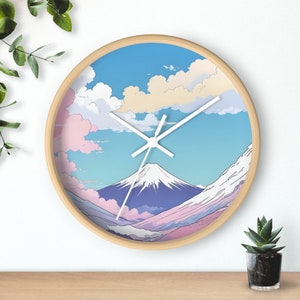 May include: Round wall clock with a light wood frame. The clock face features a mountain landscape with a blue sky, white clouds, and a snow-capped mountain. White clock hands indicate the time.