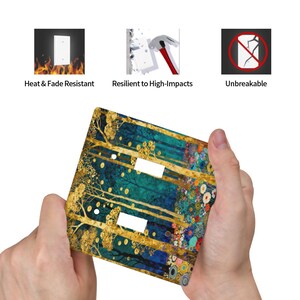 May include: A decorative light switch cover featuring a forest design with gold trees and colorful floral accents. The cover is held by hands and has cutouts for two switches. Text on the image reads "Heat & Fade Resistant", "Resilient to High-Impacts", and "Unbreakable".