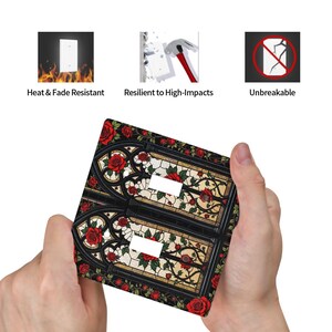 May include: A decorative light switch cover featuring a stained glass design with red roses and green leaves. The cover has two switch openings and is black with a floral pattern. The image also shows icons with the text: Heat & Fade Resistant, Resilient to High-Impacts, and Unbreakable.