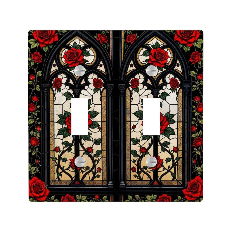 May include: A decorative double light switch cover featuring a gothic stained-glass design. The black frame is adorned with red roses and green leaves. The stained-glass panels have a cream and tan background. The light switches are silver.