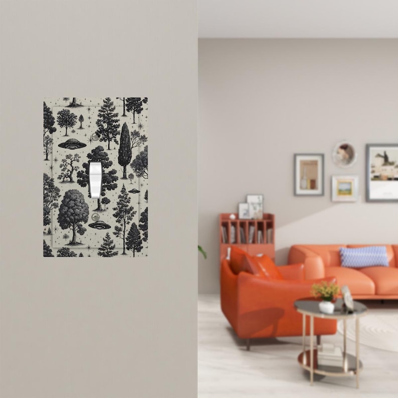 Op de afbeelding: Een lichtschakelaarcover met een zwart-wit bosontwerp. De cover heeft verschillende boomillustraties en UFO's op een lichtbeige achtergrond. De schakelaar is wit en gecentreerd.