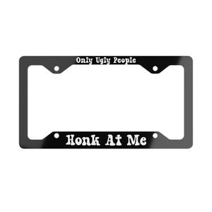 Puede incluir: Un marco rectangular negro para matrícula con texto blanco impreso en los bordes superior e inferior. El borde superior muestra las palabras Only Ugly People, mientras que el borde inferior muestra Honk At Me en una fuente negrita y redondeada.