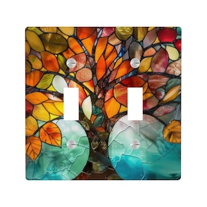 Puede incluir: Cubierta decorativa para interruptor doble con diseño de vidriera de un árbol con hojas coloridas. Las hojas son en tonos naranja, amarillo y rojo, con una base turquesa y verde. La cubierta tiene dos aberturas para interruptores.