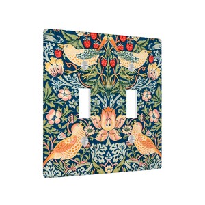 Puede incluir: Una cubierta decorativa para interruptor de luz doble con un patr&oacute;n repetido de p&aacute;jaros, flores y bayas en tonos naranja, amarillo y rosa sobre un fondo azul oscuro. El dise&ntilde;o tiene una est&eacute;tica vintage y bot&aacute;nica.