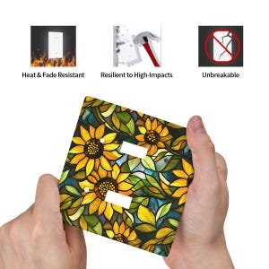 May include: A decorative light switch cover featuring a stained-glass sunflower design. The cover has two switch openings and is adorned with yellow sunflowers, green leaves, and blue accents. The image also shows icons indicating heat and fade resistance, high-impact resilience, and unbreakable construction.