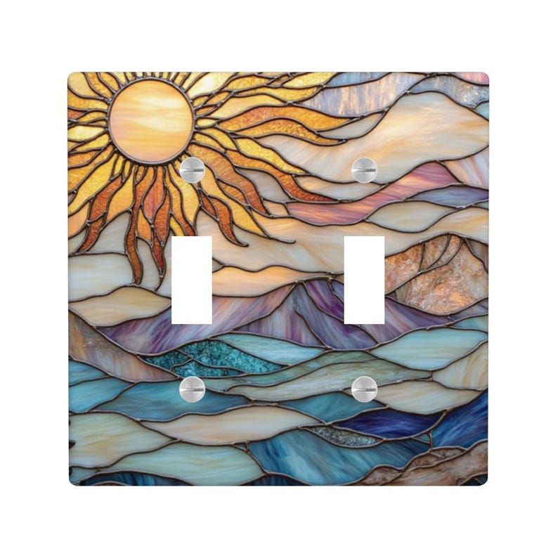 May include: A decorative double light switch cover with a stained glass design. The artwork shows a sun with yellow and orange rays, above a landscape of mountains and water in shades of blue, purple, and beige.