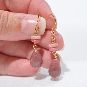 Peut inclure: Une paire de boucles d'oreilles pendantes avec des crochets en fil dor&eacute;, de petites perles rondes en pierre rose et des pendentifs plus grands en forme de goutte en pierre vieux rose, reli&eacute;s par des &eacute;l&eacute;ments m&eacute;talliques dor&eacute;s.