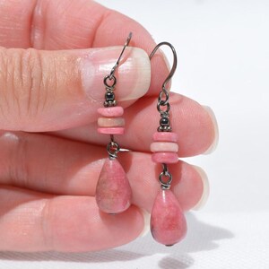Peut inclure: Une paire de boucles d'oreilles pendantes avec des crochets en m&eacute;tal fonc&eacute;, de petites perles sombres, deux disques en pierre rose empil&eacute;s et un pendentif en pierre rose en forme de goutte. Les pierres pr&eacute;sentent des variations naturelles.