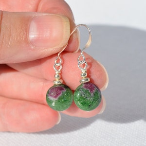 May include: A pair of silver earrings with green and pink gemstone beads.