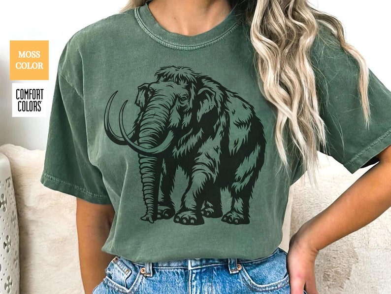May include: A green t-shirt with a black and white illustration of a woolly mammoth. The mammoth is facing forward with its tusks visible.