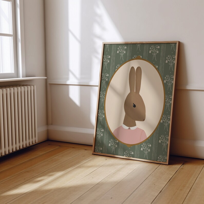 May include: A framed illustration of a brown rabbit wearing a pink shirt, set against a green background with a floral pattern.