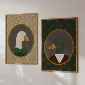 May include: Two framed illustrations of a goose and a duck wearing formal attire. The goose is wearing a green bow tie and the duck is wearing a brown jacket and white collar. The goose illustration has a gold background with a brown floral pattern. The duck illustration has a green background with a clover pattern.
