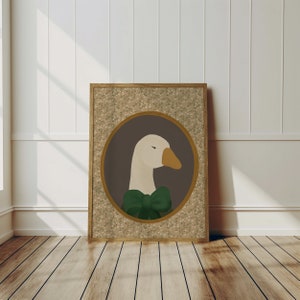 May include: A framed print of a white goose wearing a green bow tie. The goose is in a circular frame with a brown background and a floral pattern border.