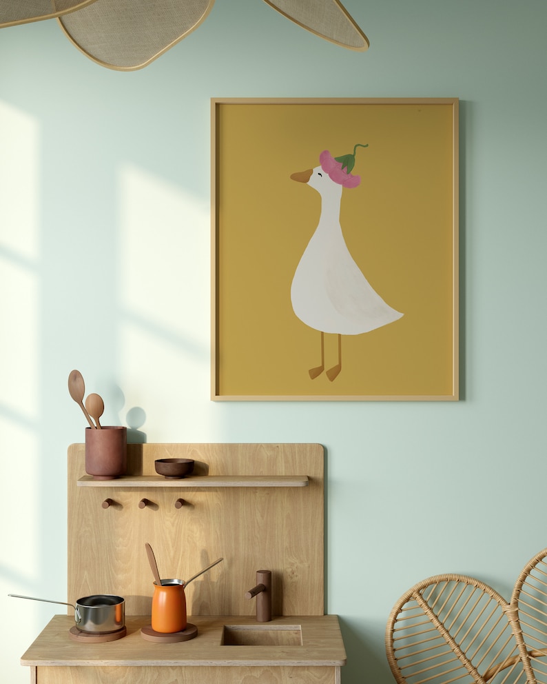May include: A framed illustration of a white goose wearing a pink flower on its head. The goose is standing on a yellow background.