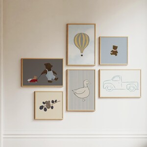 K&ouml;nnte beinhalten: Eine Sammlung gerahmter Drucke mit verschiedenen Illustrationen, darunter ein B&auml;r, der einen Wagen schiebt, eine Ente, ein LKW, ein Hei&szlig;luftballon und ein B&auml;r mit Hut. Die Drucke sind an einer wei&szlig;en Wand angeordnet.