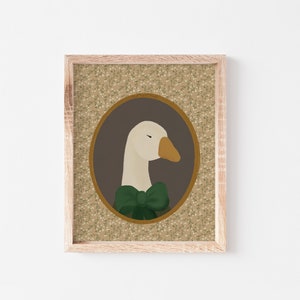 May include: A framed illustration of a white goose wearing a green bow tie. The goose is in a brown oval frame with a floral pattern background.