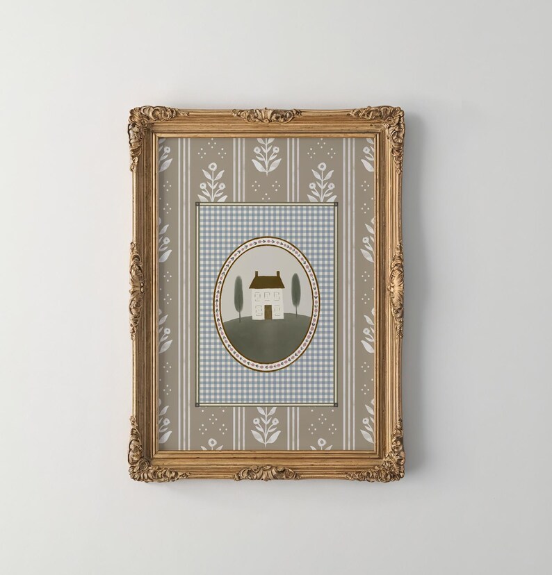 May include: A framed print of a house with a brown roof and white walls, surrounded by two green trees. The house is set against a blue and white checkered background with a floral pattern border. The frame is gold with ornate details.