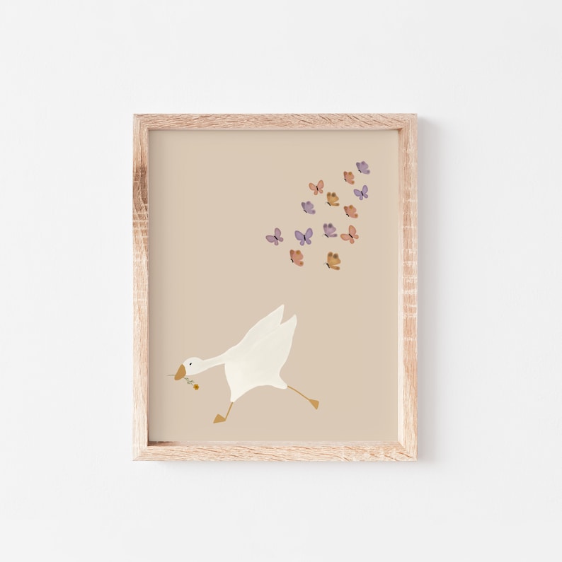 May include: A framed print with a white goose running towards a flock of purple and orange butterflies on a beige background.
