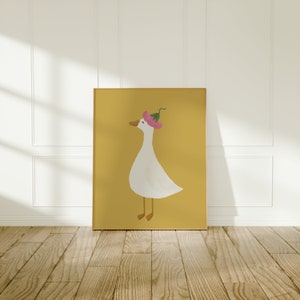May include: A framed illustration of a white goose wearing a pink flower on its head. The goose is standing on a yellow background.