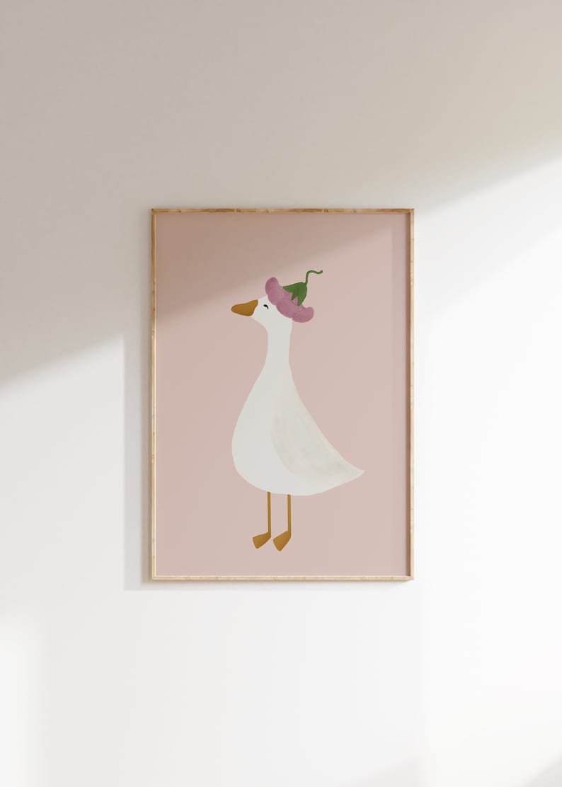 May include: A framed illustration of a white goose wearing a pink flower on its head. The background is a light pink color.
