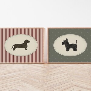 May include: Two framed dog art prints. One features a dachshund silhouette on a cream oval against a red and white striped background. The other shows a Scottish Terrier on a cream oval against a green patterned background.