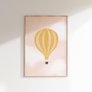 May include: A framed print of a yellow hot air balloon with white stripes floating in a pink sky with white clouds.