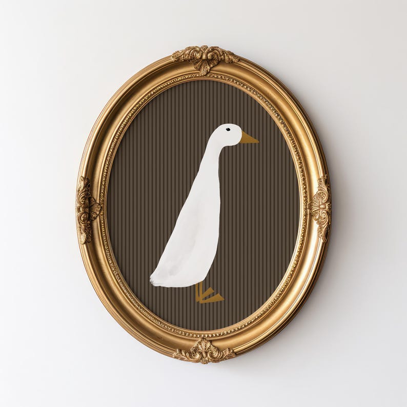 Pode incluir: Obra de arte oval com moldura dourada com uma ilustra&ccedil;&atilde;o de um pato branco sobre um fundo castanho listrado. O pato tem bico e p&eacute;s amarelos. A moldura tem detalhes ornamentais e est&aacute; colocada numa parede branca.