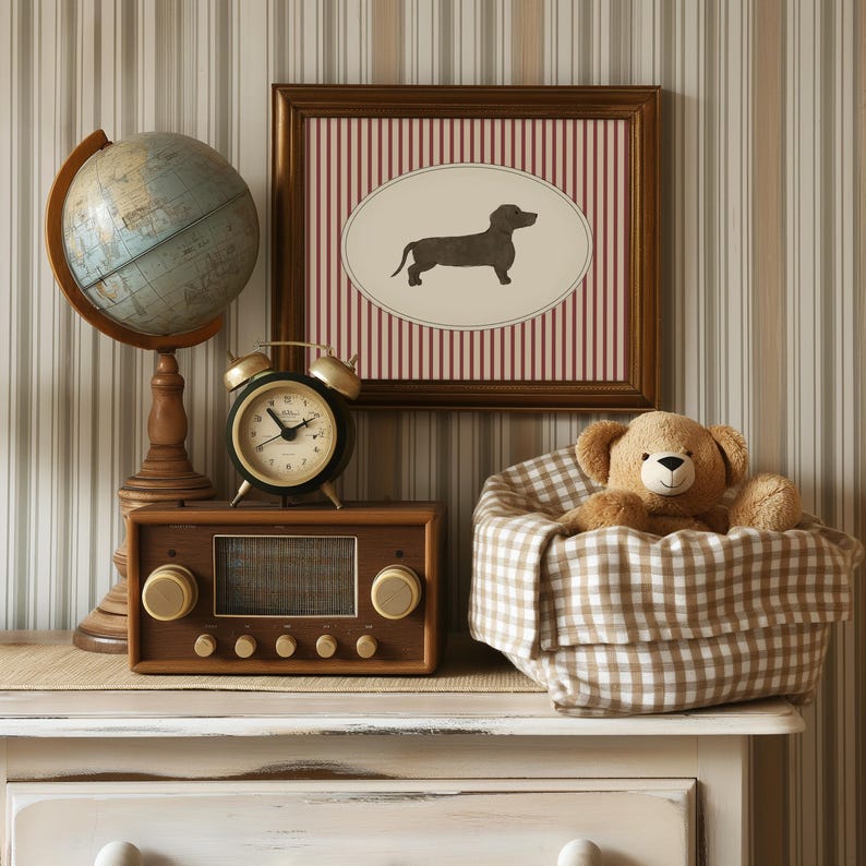 May include: A vintage-themed vignette featuring a globe, a framed dachshund print, a teddy bear in a gingham basket, a retro radio, and a brass alarm clock. The items are arranged on a white dresser against a striped wallpaper background.