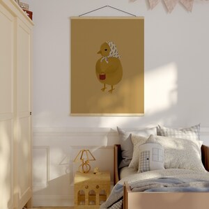 Puede incluir: Una ilustraci&oacute;n marr&oacute;n y amarilla de un pollito sosteniendo una taza roja. El pollito lleva un pa&ntilde;uelo estampado en blanco y azul. La ilustraci&oacute;n est&aacute; impresa en lienzo y enmarcada con un marco de madera.