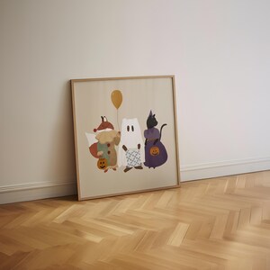 Puede incluir: Una ilustraci&oacute;n enmarcada de tres animales vestidos con disfraces de Halloween. Un zorro con un disfraz de buf&oacute;n, un fantasma con una s&aacute;bana blanca y un gato negro con un vestido morado. Los animales sostienen calabazas y un globo amarillo.