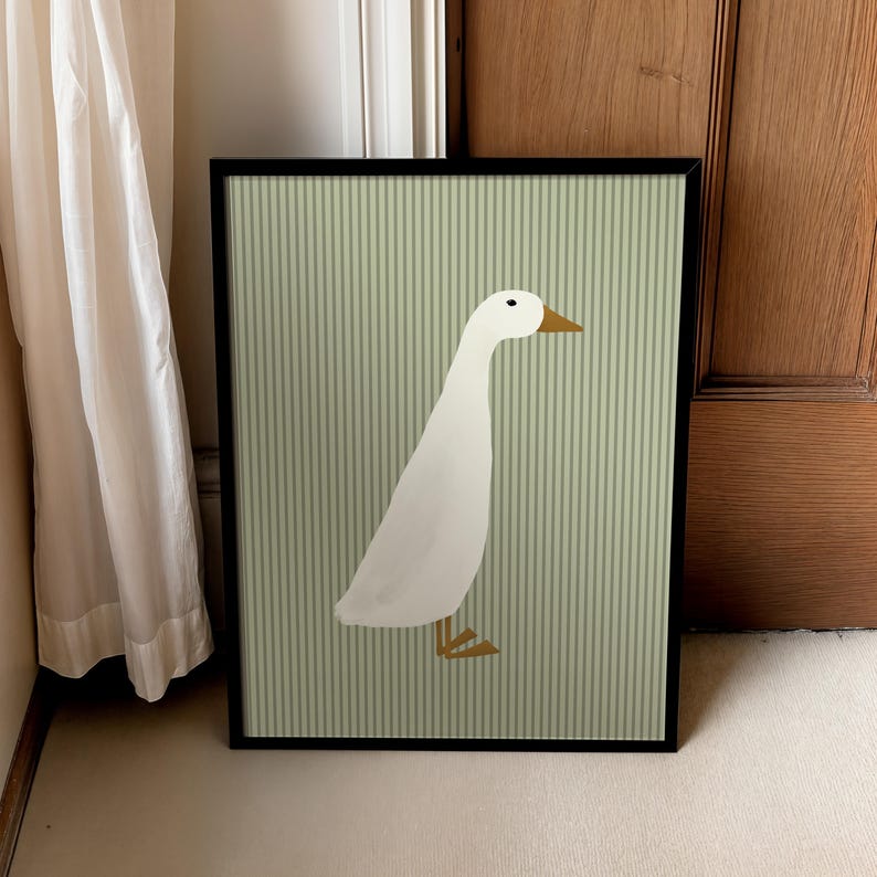 May include: A framed print of a white duck on a green and white striped background.