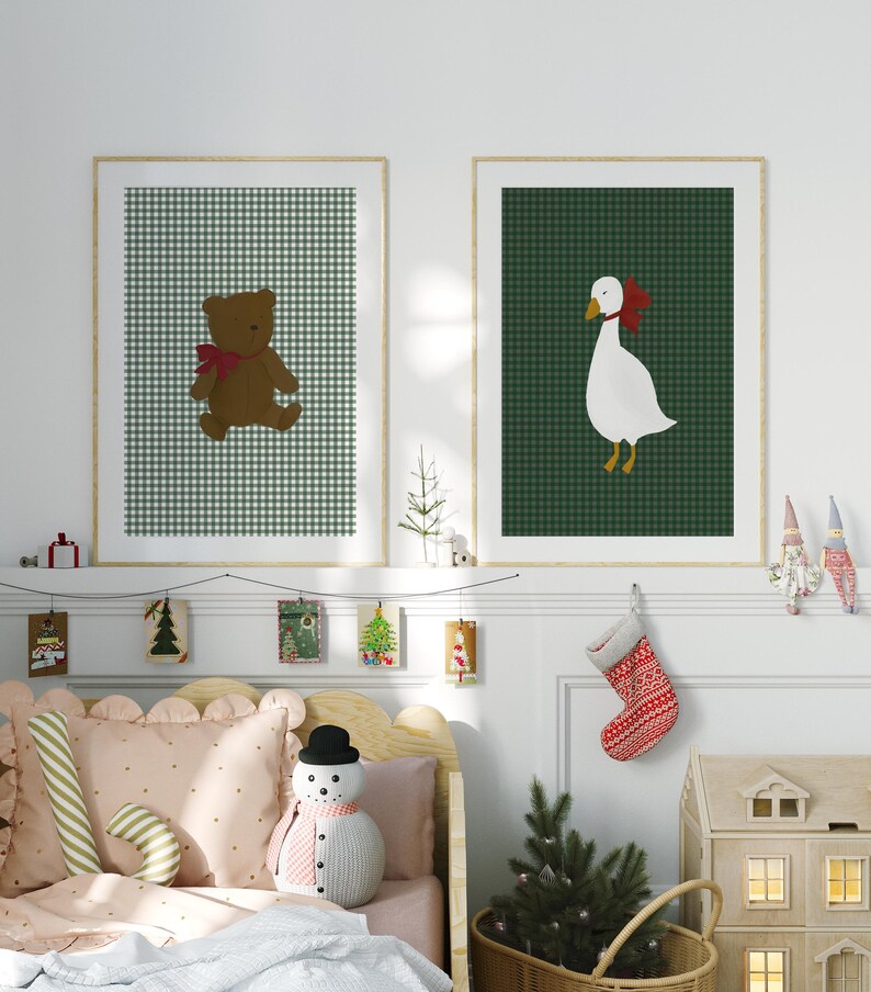 May include: Two framed illustrations of a teddy bear and a goose wearing red bows on a green and white gingham background. The frames are hanging on a white wall above a bed with a pink and white patterned duvet and a snowman plush toy.