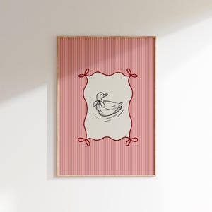 May include: A pink and white striped poster with a red frame and a black and white illustration of a duck inside a red frame with red bows.