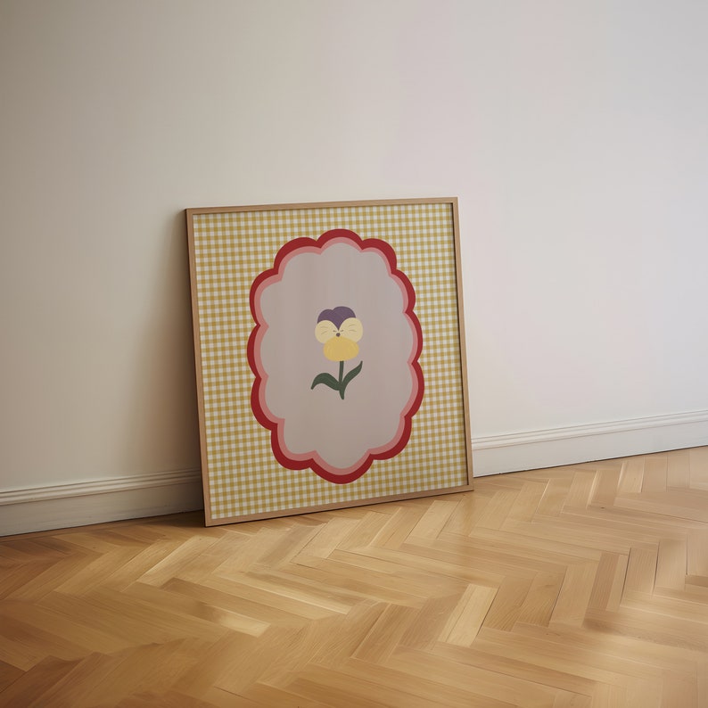May include: A framed print with a yellow and purple flower on a gingham background.