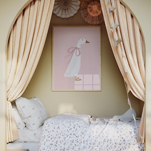 May include: A white goose with a pink bow sits on a pink and white striped background in a framed picture. The picture is hanging on a wall in a room with a bed and curtains.