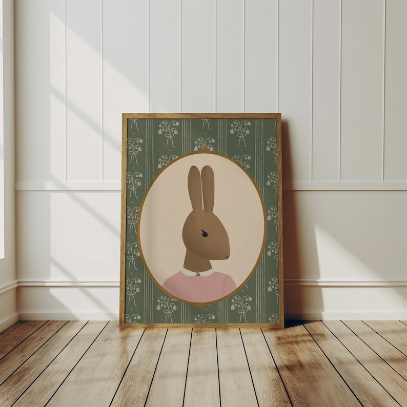 May include: A framed illustration of a brown rabbit wearing a pink shirt, set against a green background with a floral pattern.