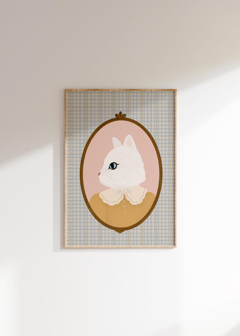 May include: A white cat with blue eyes wearing a yellow shirt with a lace collar is depicted in a pink oval frame with a gold border. The frame is set against a blue and white checkered background.