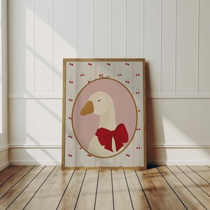 May include: A framed illustration of a white goose with a red bow, set against a pink background with a pattern of red cherries on a white and brown striped background.