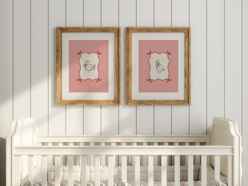 May include: Two framed prints with a pink and white striped background. Each print features a black and white illustration of a duck inside a red and white frame. The frames are made of wood and have a natural finish.