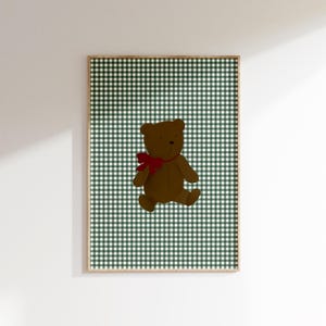 May include: A framed print of a brown teddy bear with a red bow, sitting on a green and white gingham background.