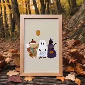 Puede incluir: Una ilustraci&oacute;n enmarcada de un zorro, un fantasma y un gato vestidos con disfraces de Halloween. El zorro lleva un disfraz de buf&oacute;n, el fantasma lleva una s&aacute;bana blanca y el gato lleva un vestido morado. Todos llevan calabazas talladas. El fondo es de color beige claro.