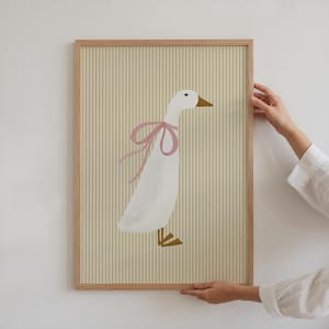 May include: A framed illustration of a white goose with a pink bow on a yellow and white striped background.