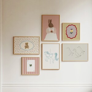 May include: A collection of framed prints with various designs, including a rabbit, a teddy bear, a flower, ducks, and a carousel horse. The prints are all in pastel colors and have a whimsical feel.