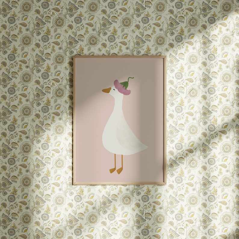 May include: A framed print of a white goose wearing a pink flower on its head. The goose is standing on a pink background. The frame is made of wood and has a light brown finish.