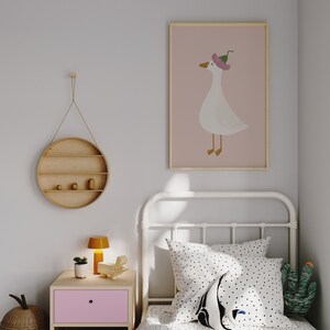 May include: A white metal bed frame with a white and black polka dot duvet cover and a white pillow with black polka dots. A white goose with a pink flower on its head is pictured in a framed print on the wall. A small wooden shelf with two small wooden figurines is hanging on the wall.