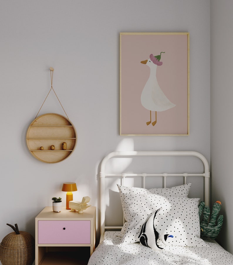 May include: A white metal bed frame with a white and black polka dot duvet cover and a white pillow with black polka dots. A white goose with a pink flower on its head is pictured in a framed print on the wall. A small wooden shelf with two small wooden figurines is hanging on the wall.