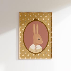 May include: A framed illustration of a brown rabbit wearing a yellow and white sweater with a pink bow. The rabbit is in an oval frame with a pink background. The frame is on a yellow background with a white floral pattern.